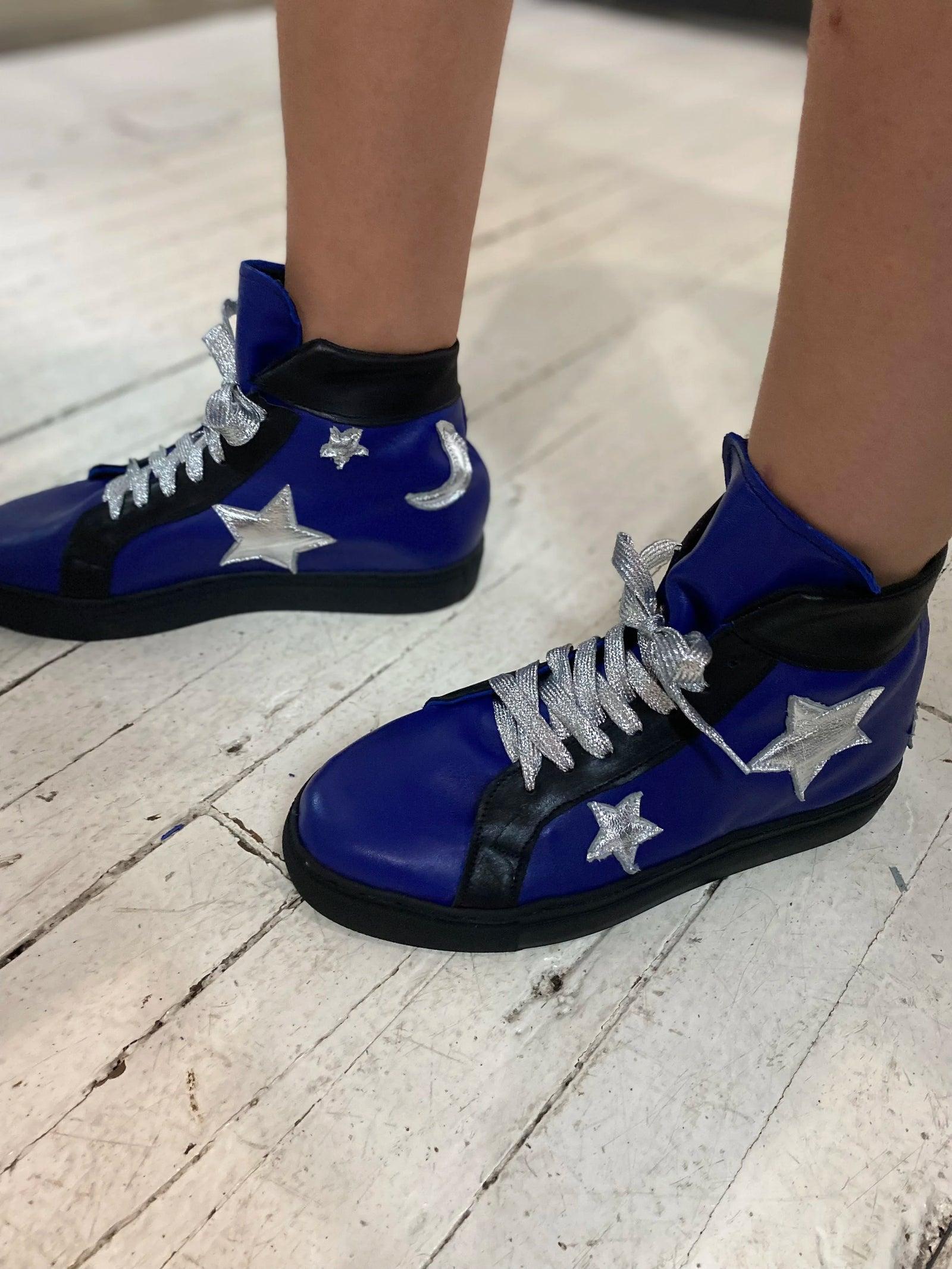Hand-made blue leather high-top sneakers with silver stars, worn on the studio floor